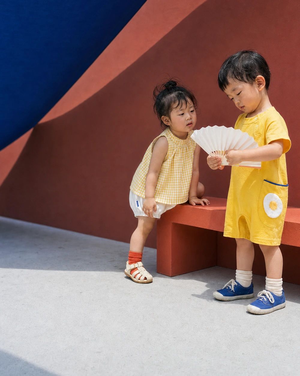 夏のテラスで紙の扇を広げるベビーの男の子と女の子